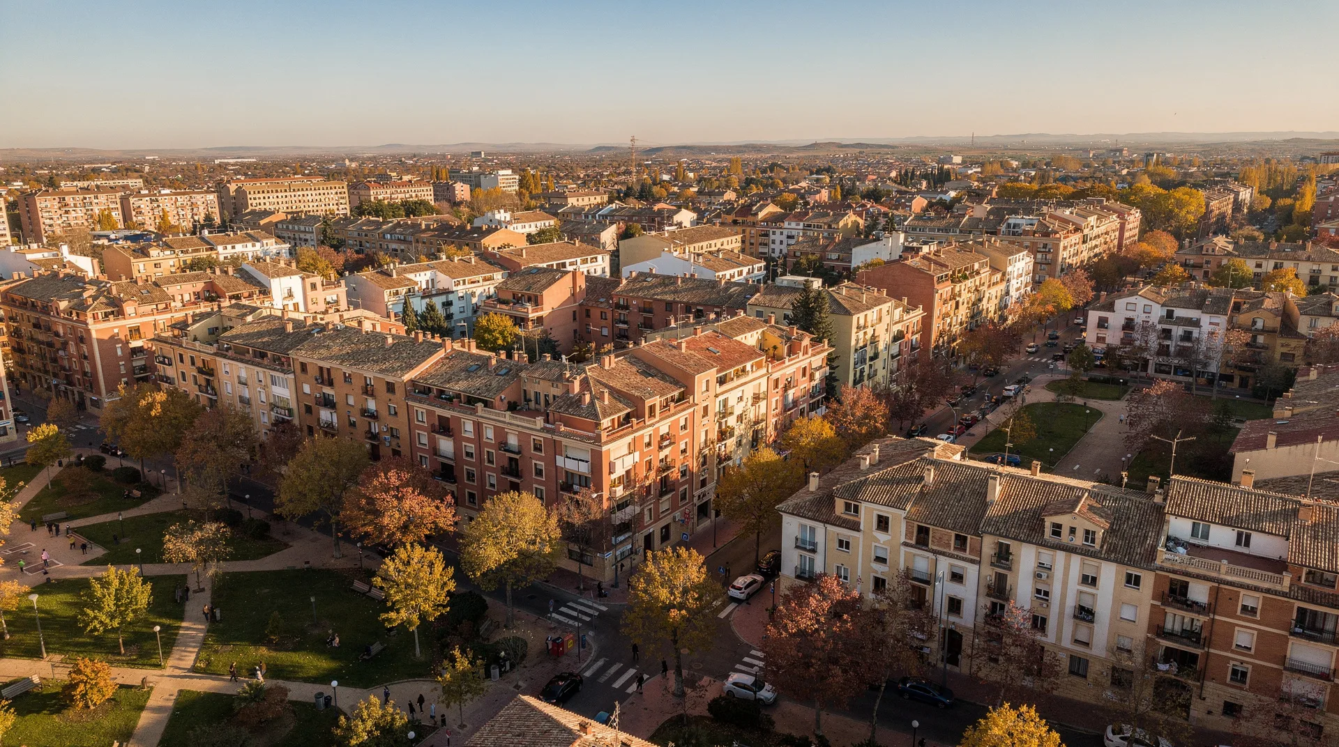 Vista aérea de un barrio residencial de ciudad mediana española con bloques de pisos y zonas verdes en otoño